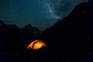 Nacht Berglandschaft mit beleuchtetem Zelt foto