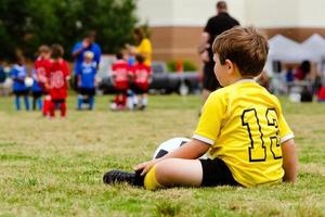 Kind in Uniform beobachtet organisierten Jugendfußball foto