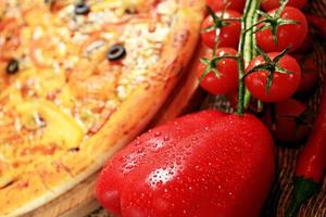Pizza mit rustikalem Hintergrund von Gemüse und Kräutern foto