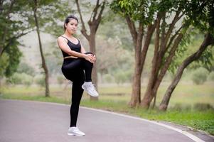 eine schöne asiatische frau wärmt sich auf, um die muskeln flexibel zu machen, bevor sie zum joggen geht foto