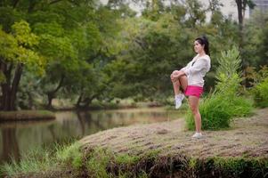 eine schöne asiatische frau wärmt sich auf, um die muskeln flexibel zu machen, bevor sie zum joggen geht foto