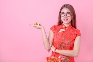asiatische frau in chinesischen nationalen kostümen hält ein glückliches gold für das chinesische neujahrsereignis foto
