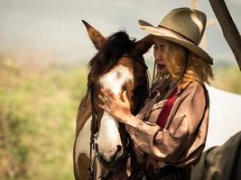 Cowgirl berührt das Pferd mit Liebe wegen Beziehungen, die Freunde sind, die Leiden und Glück miteinander teilen foto