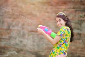 Schöne asiatische Frauen halten während Songkran, dem schönsten und lustigsten Wasserfest in Thailand, Plastikwasserpistolen in einem alten Tempel foto