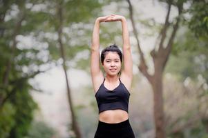 eine schöne asiatische frau wärmt sich auf, um die muskeln flexibel zu machen, bevor sie zum joggen geht foto