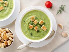 zwei große weiße schüssel mit gemüsegrüner cremesuppe aus brokkoli, zucchini, grünen erbsen foto