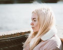 Porträt eines jungen Mädchens, blond mit gebleichtem Haar, kaukasisch. skandinavischer Stil. Nahaufnahme einer Teenager-Frau, die an einer Kamera in der Stadt in der Nähe von Wasser vorbeischaut. foto
