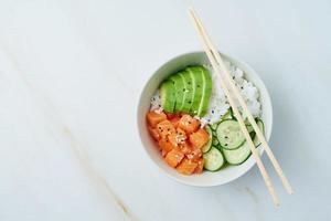 Lachs-Poke-Bowl mit frischem Fisch, Reis, Gurke, Avocado foto