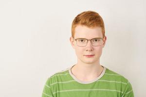 Rothaariger junger Mann mit Brille auf weißem Hintergrund foto