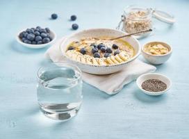 glas sauberes wasser und gesundes diätfrühstück mit haferflocken, blaubeeren, banane foto