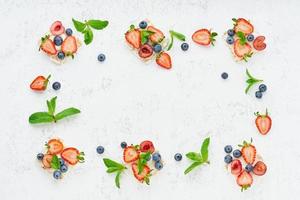 Knäckebrotrahmen mit Beeren und Früchten buntes Konzept auf pastellfarbenem Hintergrund kopieren foto