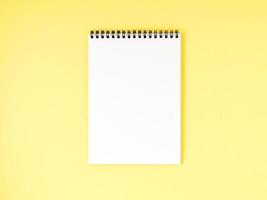 weiße Seite des leeren Notizblocks auf gelbem Schreibtisch, farbiger Hintergrund. Draufsicht, leerer Platz für Text. foto