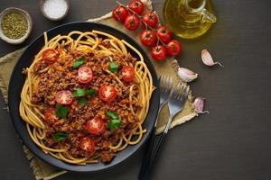 Pasta Bolognese Bucatini mit Hackfleisch und Tomaten, dunkler Holzhintergrund, Draufsicht, Kopierraum