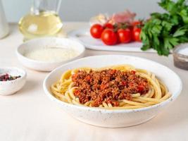 Pasta Bolognese mit Tomatensauce, Rinderhackfleisch, Basilikumblätter im Hintergrund