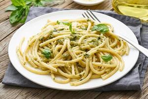 Pesto-Spaghetti-Nudeln mit Basilikum, Knoblauch, Pinienkernen, Olivenöl. rustikaler Tisch, Nahaufnahme