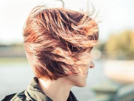 schöne Frau, mit braunen Haaren, die im Wind flattern. Sonniger Herbsttag, Straße im Stadtzentrum, foto