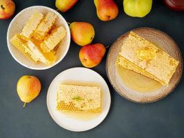 Honig in Waben, Nahaufnahme, auf weißer Keramikplatte, auf rustikalem Holztisch, Seitenansicht, Sonnenlicht foto