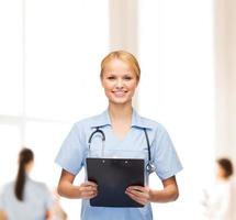 lächelnde Ärztin oder Krankenschwester mit Zwischenablage