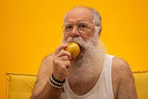 Porträt eines bärtigen Mannes, der kurz davor steht, einen Apfel zu essen. Senior, der einen Apfel hat. foto