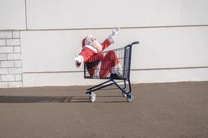 Supermarktwagen mit Weihnachtsmann im Inneren. einkaufen für weihnachtskonzept. foto