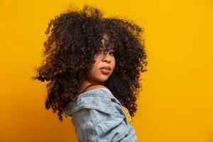 Schönheitsporträt einer afroamerikanischen Frau mit Afro-Frisur und Glamour-Make-up. brasilianische Frau. gemischtrassig. Lockige haare. Frisur. gelber Hintergrund. foto