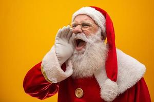 Kommunikationskonzept. profilseitenansichtfoto des aufgeregten, lustigen, stilvollen weihnachtsmanns mit offenem mund, der handfläche in der nähe des gesichts hält und lautes ho-ho-ho sagt, isoliert auf leuchtend gelbem hintergrund foto