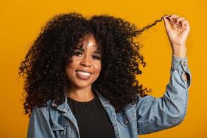 junge afroamerikanische frau mit lockigem haar, die in die kamera schaut und lächelt. süßes Afro-Mädchen mit lockigem Haar, das in die Kamera lächelt. foto