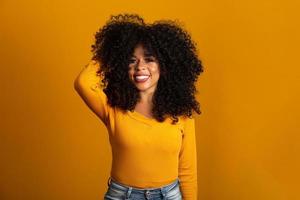 junge afroamerikanische frau mit lockigem haar, die in die kamera schaut und lächelt. süßes Afro-Mädchen mit lockigem Haar, das in die Kamera lächelt. foto