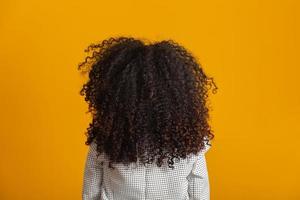 junge schwarze Frau auf dem Rücken mit Afro-Frisur auf gelbem Hintergrund. Mädchen mit afrikanischer Frisur. Studioaufnahme. foto