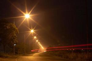 Beleuchtung von Lampen und Autolichtern auf Landstraßen bei Nacht. foto