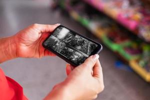 hand, die handy hält, video anschaut, cctv-kameras im shop überprüft. foto