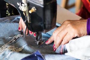 Reparatur von Jeans mit rotem Nagel von Hand. foto