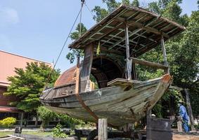 Ein altes verrottetes Holzboot wird in einen Tempel bewegt. foto