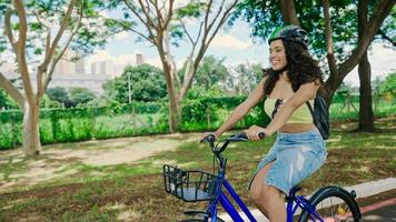 junge lateinfrau im schutzhelm fährt mit dem fahrrad auf dem radweg in einem stadtpark foto