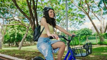 junge lateinfrau im schutzhelm fährt mit dem fahrrad auf dem radweg in einem stadtpark foto