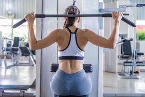 sportliche Frau mit Maschine zum Pumpen der Rückenmuskulatur im Fitnessstudio, Rückansicht foto