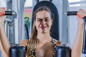 Mädchen trainiert Brust im Fitnessgerät foto