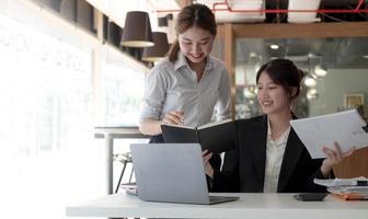 Zwei asiatische Geschäftsfrauen arbeiten zusammen, um die Arbeit im Büro zu erledigen. foto