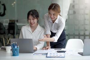 zwei junge asiatische geschäftsfrauen diskutieren mit der ideenpräsentation eines neuen startup-projekts, analysieren planungs- und finanzstatistiken sowie den investitionsmarkt im büro. foto