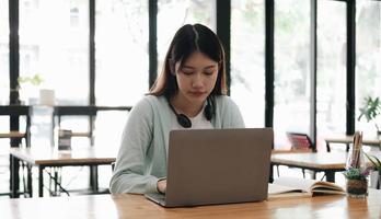 Ernsthaft fokussierter asiatischer Student, der Laptop in der Küche benutzt, mit Aufmerksamkeit und Konzentration auf den Bildschirm schaut, Lern-Webinar, virtuelles Training, Videokurs anschaut, von zu Hause aus lernt foto