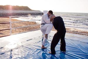 Karate-Kämpfer kämpfen morgens am Strand-Boxring foto