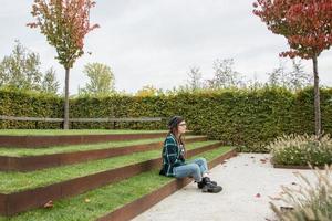 junge Frau mit roten Dreadlocks und Brille, die sich im Herbstpark entspannt foto