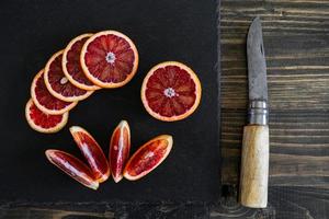 in Scheiben geschnittene sizilianische oder blutige Orangen auf schwarzem Schieferhintergrund foto