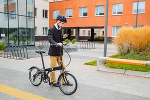 junger männlicher geschäftsmann mit fahrrad und tasse kaffee oder tee zu fuß im freien foto