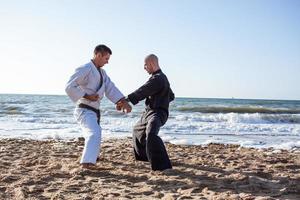 Karate-Kämpfer kämpfen morgens am Strand-Boxring foto