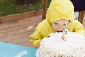 Zwei Jahre lustiges Mädchen mit Geburtstagstorte feiert im Freien foto