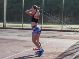 Junge starke Frau, die im Sommer im Freien trainiert, weibliche Profisportlerin macht Übungen im Park foto