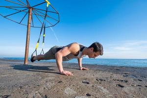 Fittes Männertraining im Sommer, Übungen mit Hängegurten im Freien foto