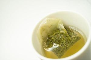 Grünteebeutel in einer Tasse. Tasse aromatischen grünen Tee auf weißem Hintergrund. Tasse mit grünem Tee in isoliert. foto