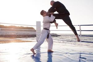 Karate-Kämpfer kämpfen morgens am Strand-Boxring foto